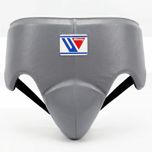 Gray protective headgear with a central logo patch, shown against a plain white background.